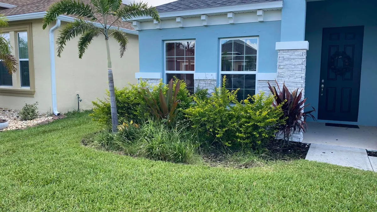 Freshly mowed, healthy green lawn in front of a light blue Florida home